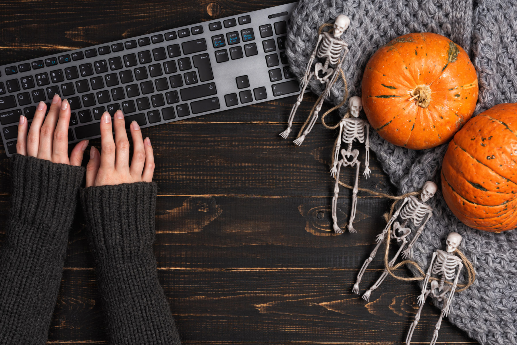 Two hands using keyboard and halloween decorations.